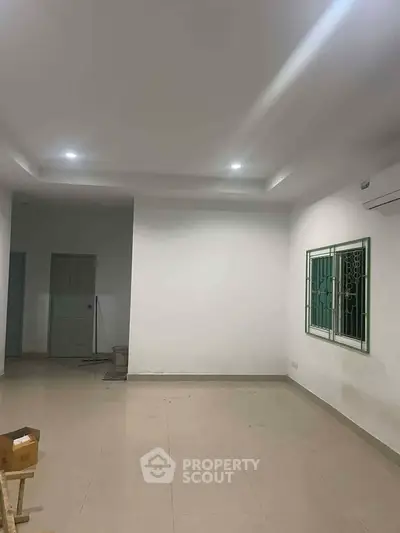 Spacious empty room with tiled flooring and modern lighting, perfect for customization.