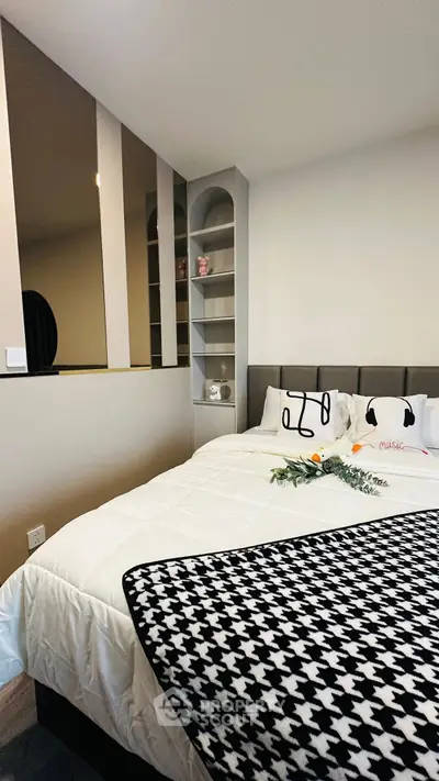 Cozy bedroom with modern decor and stylish bedding, featuring built-in shelves and elegant design elements.