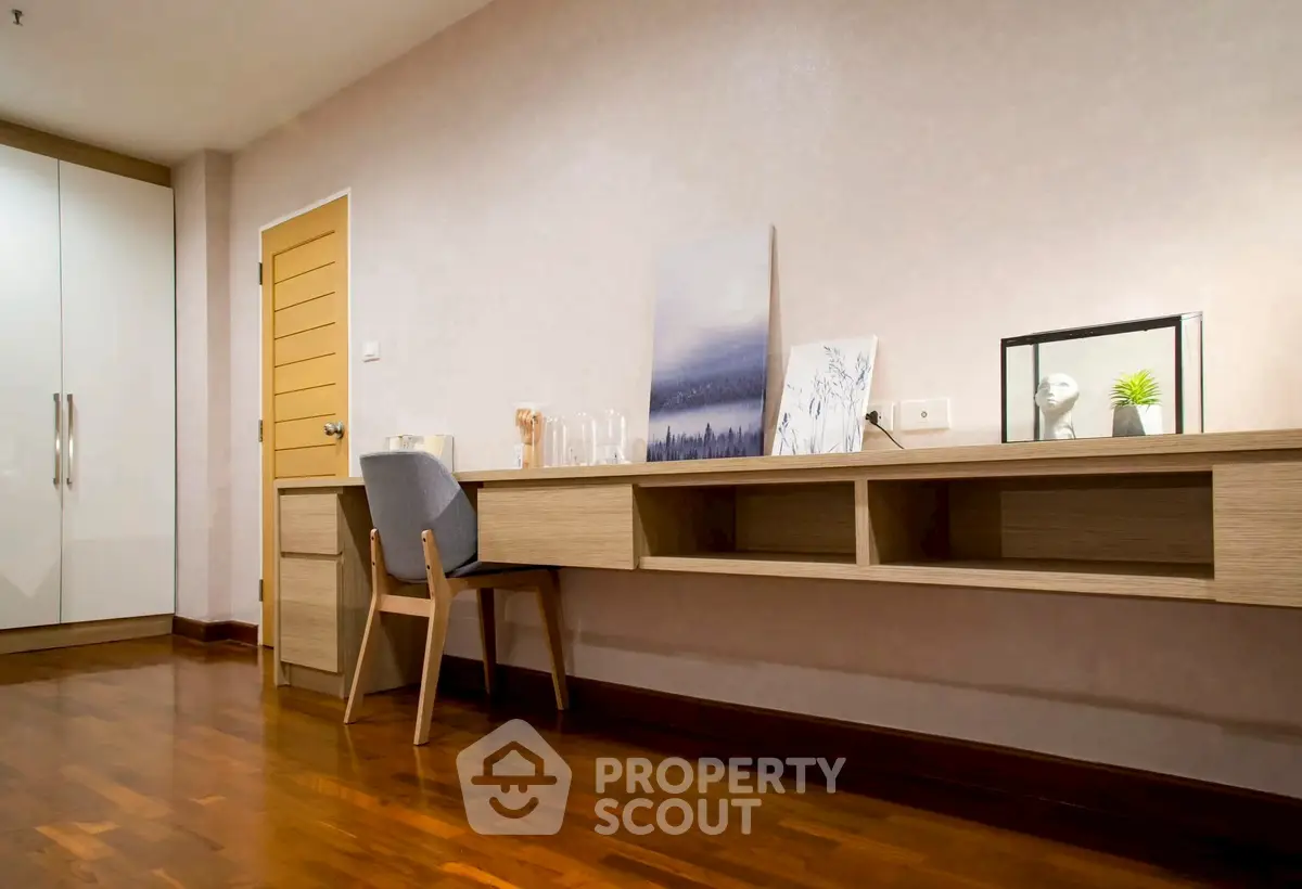 Modern study room with wooden desk and chair, featuring elegant decor and ample storage space.