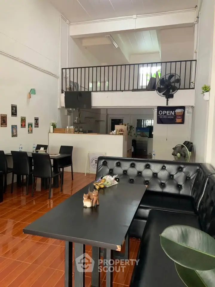 Chic open-plan living area with modern black furniture and high ceilings, perfect for entertaining.