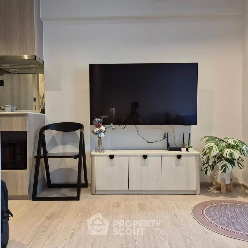 Modern living room with wall-mounted TV, sleek furniture, and stylish decor in a cozy apartment.