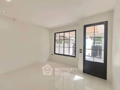 Bright and spacious room with large window and modern door, perfect for versatile living space.