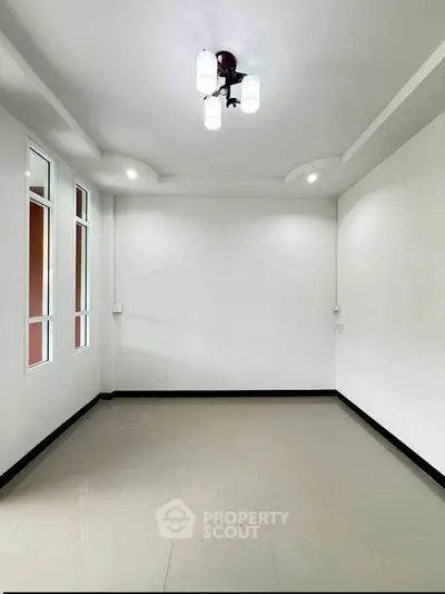 Spacious empty room with modern lighting and large windows, perfect for customization.