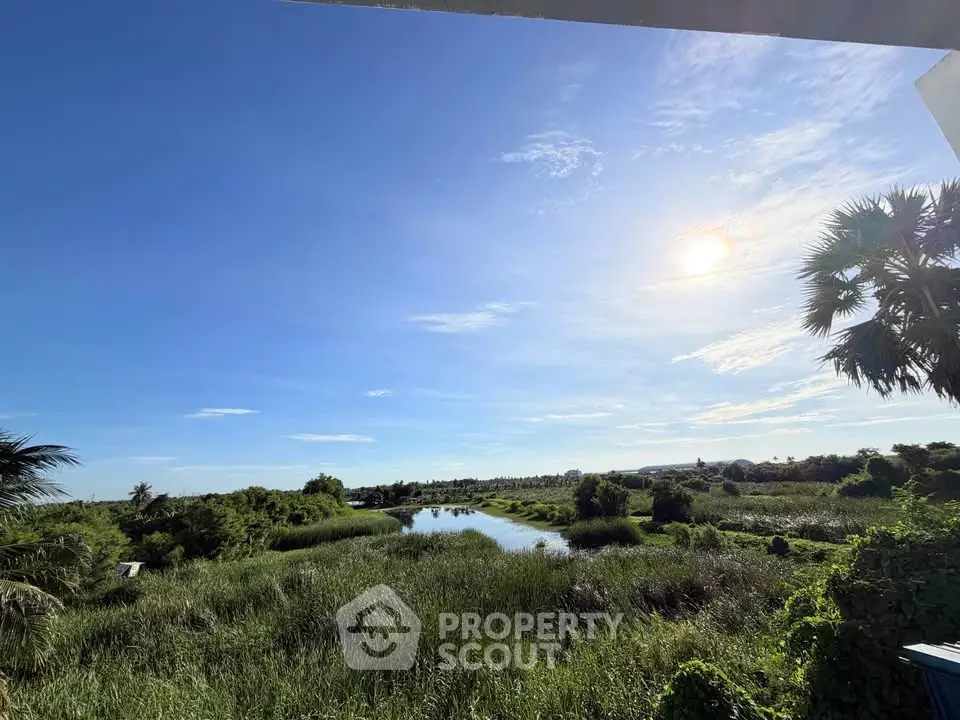 Stunning panoramic view of lush greenery and serene waterway under a clear blue sky, perfect for nature lovers.