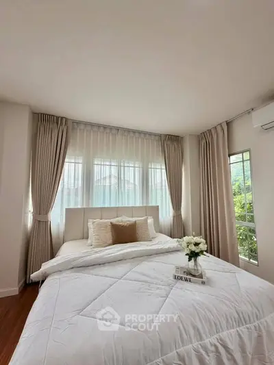 Bright and cozy bedroom with large windows and elegant curtains, perfect for relaxation.