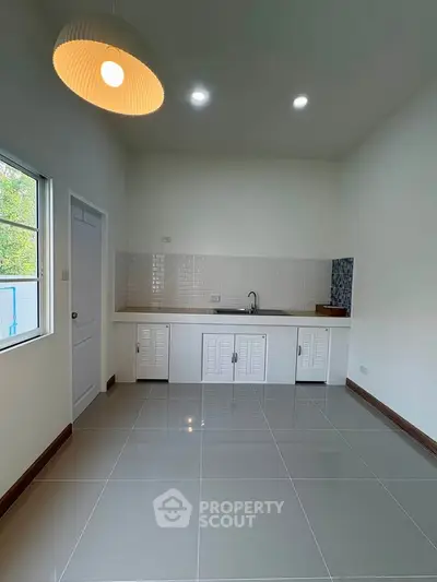 Modern kitchen with sleek white cabinets and glossy tile flooring, featuring a minimalist design and ample natural light.