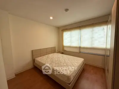 Spacious bedroom with natural light and modern furnishings in a cozy apartment.