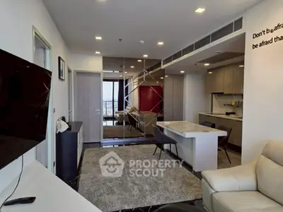 Modern living room with open kitchen, sleek design and cozy seating area.