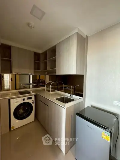 Modern compact kitchen with washing machine and fridge in sleek apartment