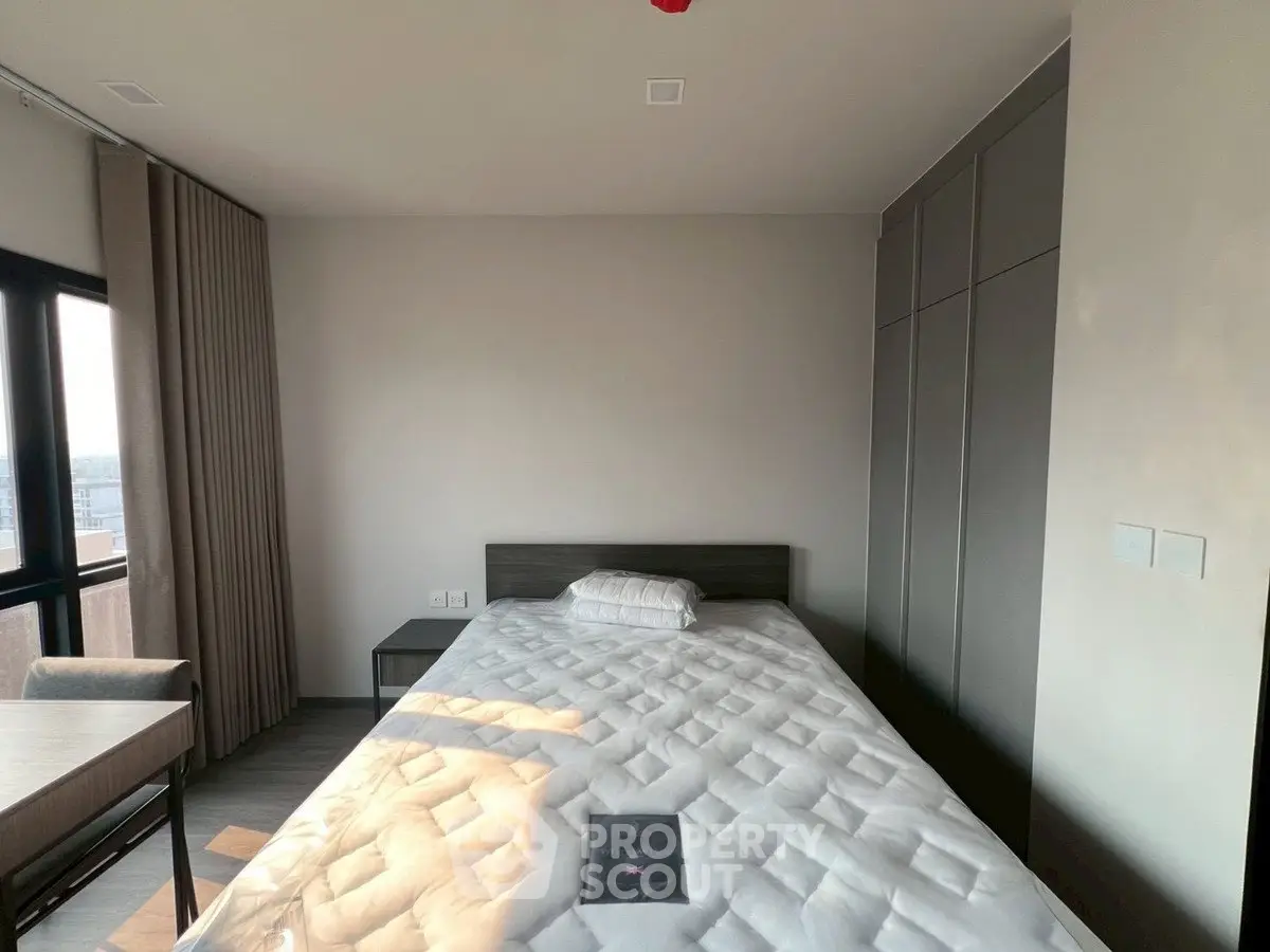 Modern bedroom with large window and built-in wardrobe, featuring a comfortable bed and sleek design.