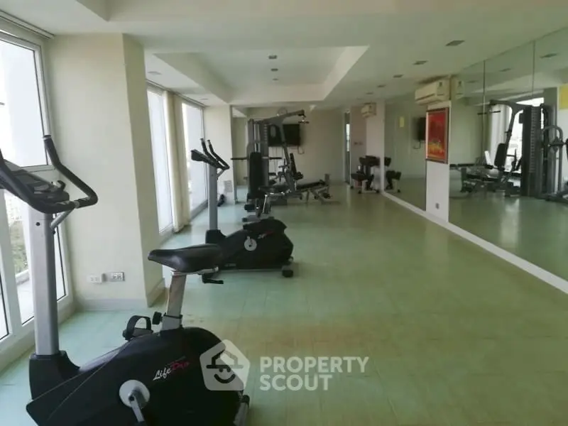Spacious gym with modern equipment and large mirrors in a bright fitness area.