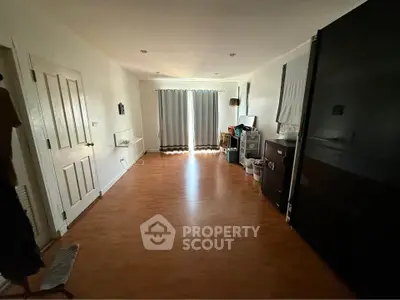 Spacious room with wooden flooring and natural light, ideal for versatile living space.