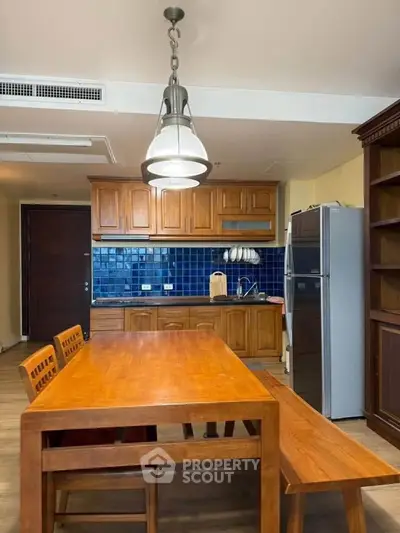 Charming kitchen with wooden cabinetry and blue tile backsplash, featuring a spacious dining table and modern appliances.