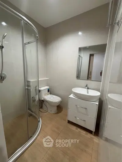 Modern bathroom with glass shower and sleek vanity in contemporary apartment.