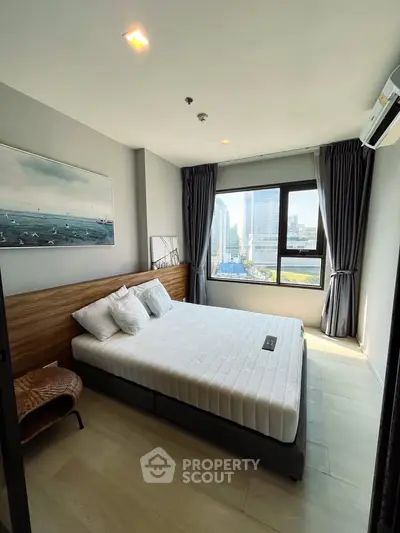 Modern bedroom with city view, featuring stylish decor and large window for natural light.