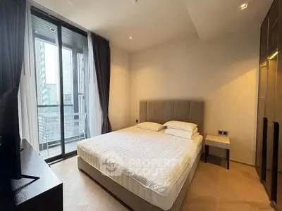 Modern bedroom with large window and balcony access in a stylish apartment.