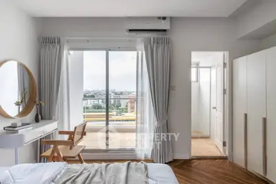 Bright bedroom with balcony access and modern decor, featuring a large window and stylish furniture.