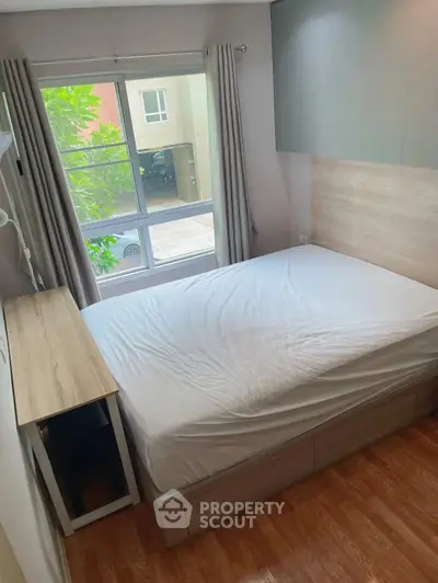 Cozy bedroom with large window and modern furnishings in a bright apartment.