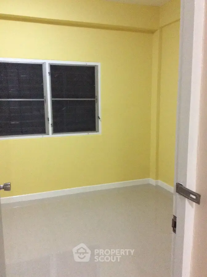 Bright yellow room with tiled floor and window, ideal for cozy living space.