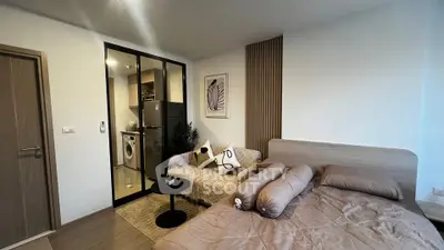 Modern bedroom with cozy bed and stylish decor, featuring a compact laundry area with washing machine.