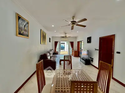 Spacious living room with elegant decor and ceiling fans, featuring a cozy seating area and dining space.