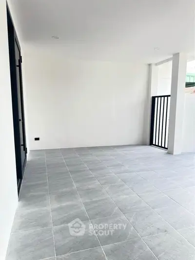 Spacious tiled balcony with modern railing and ample natural light.