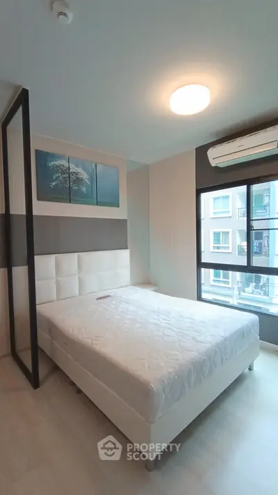 Modern bedroom with large window and stylish decor in a contemporary apartment.