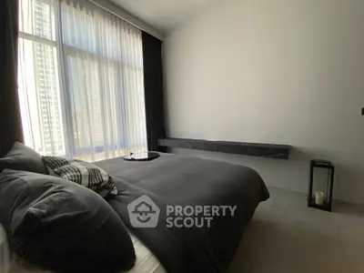 Modern bedroom with large window and sleek decor in urban apartment.