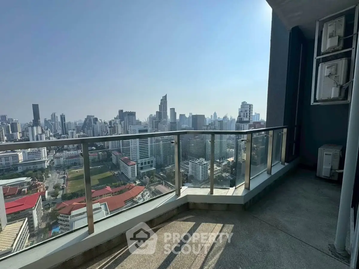 Stunning cityscape view from a high-rise balcony with glass railing, perfect for urban living.