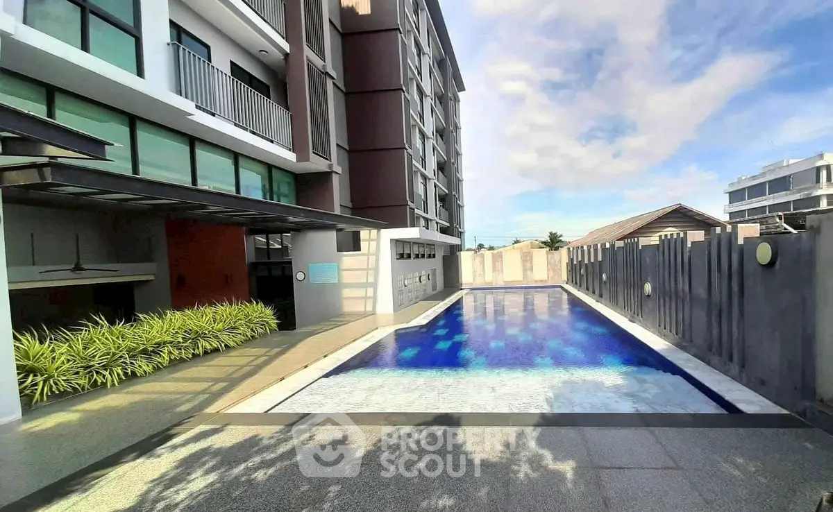 Modern apartment building with a sleek swimming pool and sunny outdoor area.