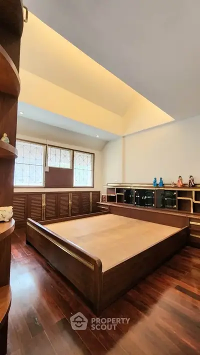 Spacious bedroom with wooden flooring and built-in storage cabinets
