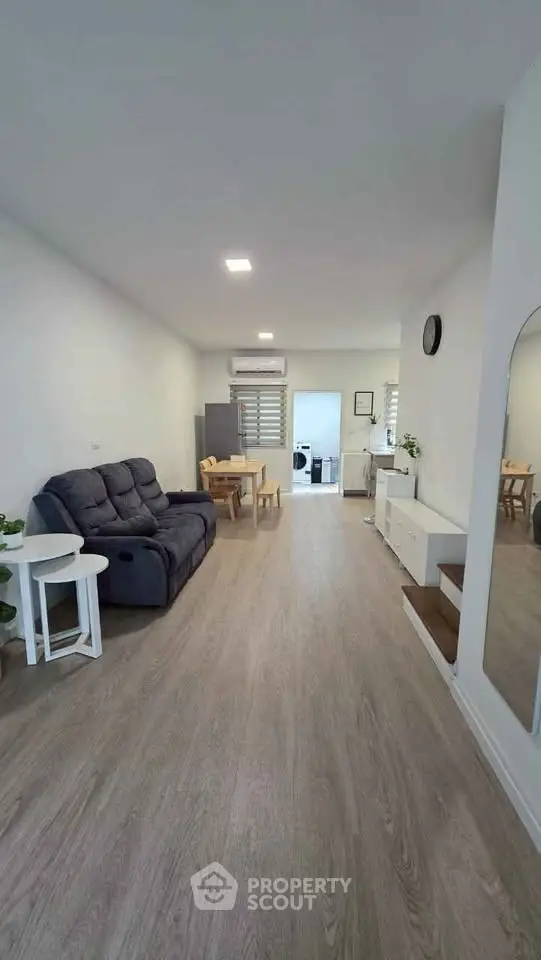 Spacious living room with modern decor and open layout, featuring a cozy sofa and dining area.