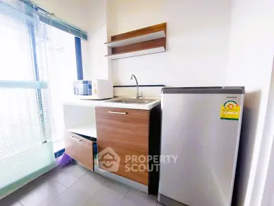 Modern kitchen with sleek cabinetry, microwave, and compact fridge in bright apartment.