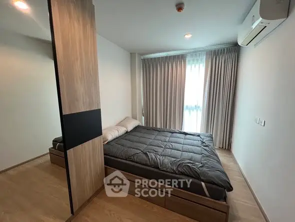 Modern bedroom with sleek design, featuring a cozy bed and natural light from large window.