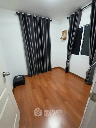 Spacious bedroom with wooden flooring and elegant curtains, perfect for a cozy retreat.