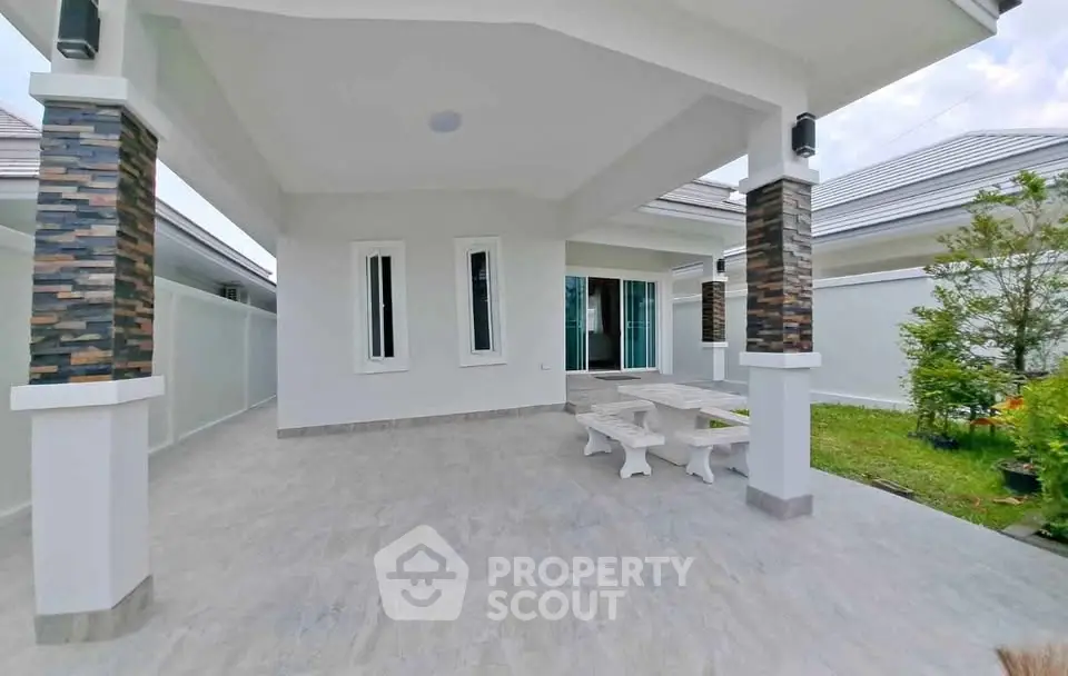 Spacious modern patio with elegant columns and garden view, perfect for outdoor relaxation.