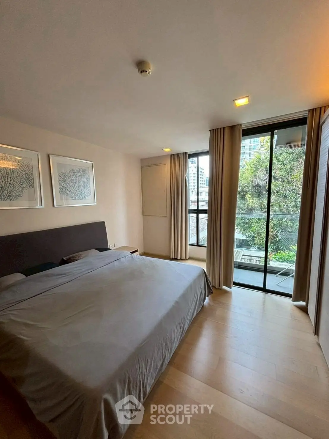 Spacious bedroom with large windows and balcony view in modern apartment.