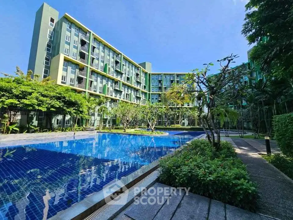 Stunning modern apartment complex with a large swimming pool and lush greenery.