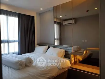 Modern bedroom with stylish mirrored wall and cozy bedding in a contemporary apartment.