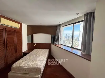 Cozy bedroom with city view, featuring a single bed and wooden accents, perfect for urban living.