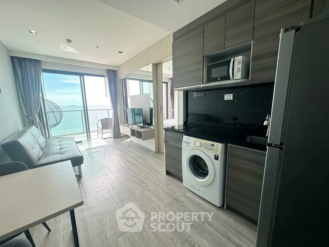 Modern apartment with ocean view, featuring sleek kitchen and cozy living area.