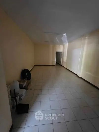 Spacious empty room with tiled flooring and neutral walls, ideal for customization.