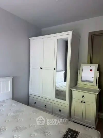 Charming bedroom with white wardrobe and matching nightstand, perfect for cozy living.
