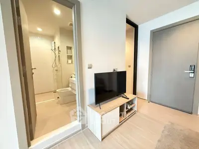 Modern apartment interior with bathroom and living area featuring sleek TV stand and wooden flooring.