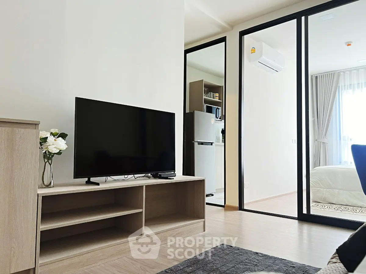 Modern apartment interior with TV, air conditioning, and open kitchen layout.