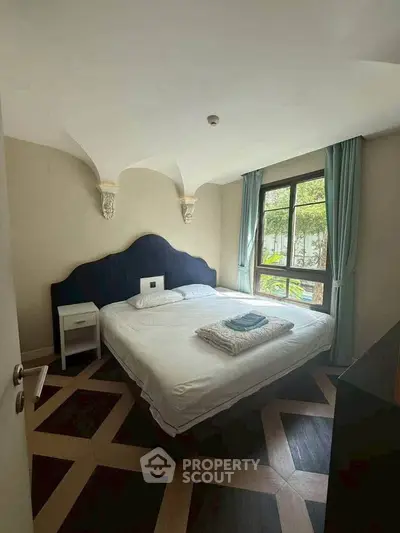 Charming bedroom with elegant decor and large window offering natural light and garden view.