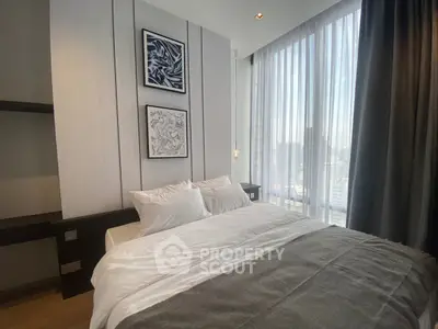 Luxurious bedroom with large windows offering stunning city views, featuring elegant decor and cozy bedding.
