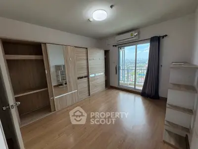 Spacious bedroom with wooden flooring and city view balcony in modern apartment.