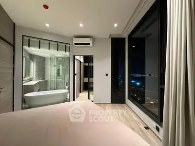 Luxurious bedroom with ensuite bathroom and stunning city view at night.