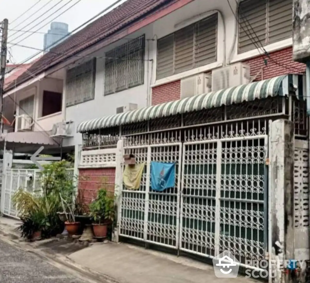 Charming urban townhouse with gated entrance and striped awning, perfect for city living.